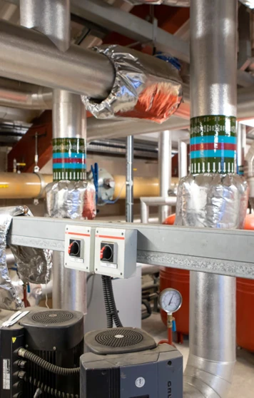 Close-up of interconnected heating system pipes, pumps, and insulated valves used for industrial heating and ventilation. Close-up of interconnected heating system pipes, pumps, and insulated valves used for industrial heating and ventilation.